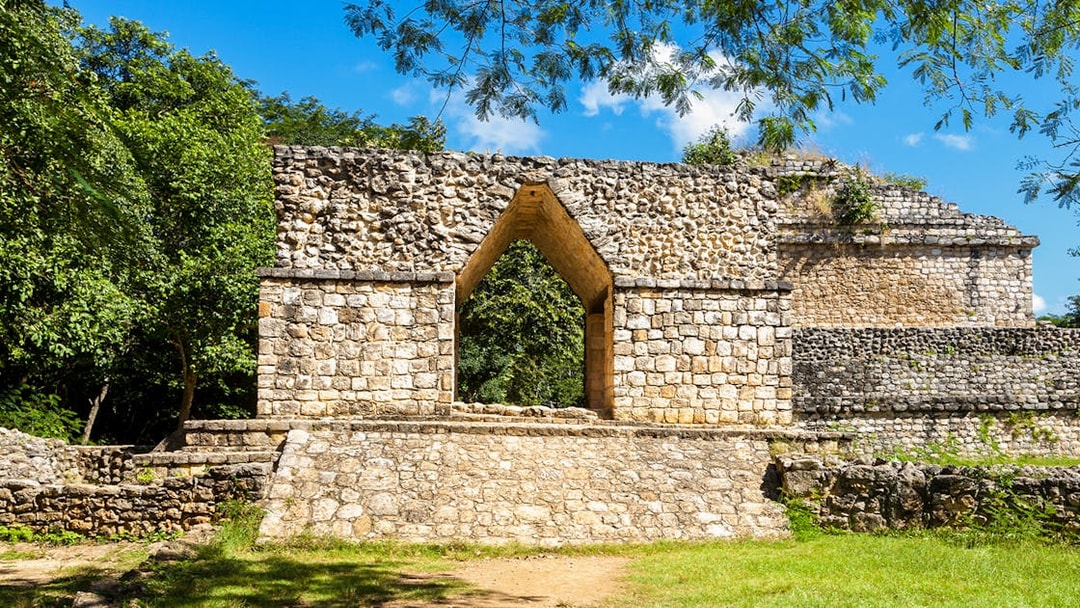 Entrance arch at Ek Balam ruins, Yucatan, Mexico, surrounded by lush greenery.