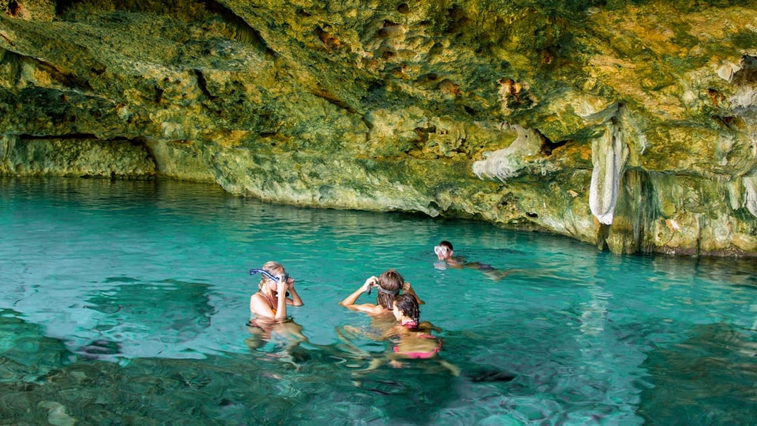 Tourists snorkeling in a cenote, Yucatan Peninsula, Mexico, surrounded by limestone formations.
