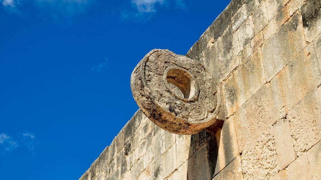 Chichen Itza Ball Court stone ring against a blue sky.