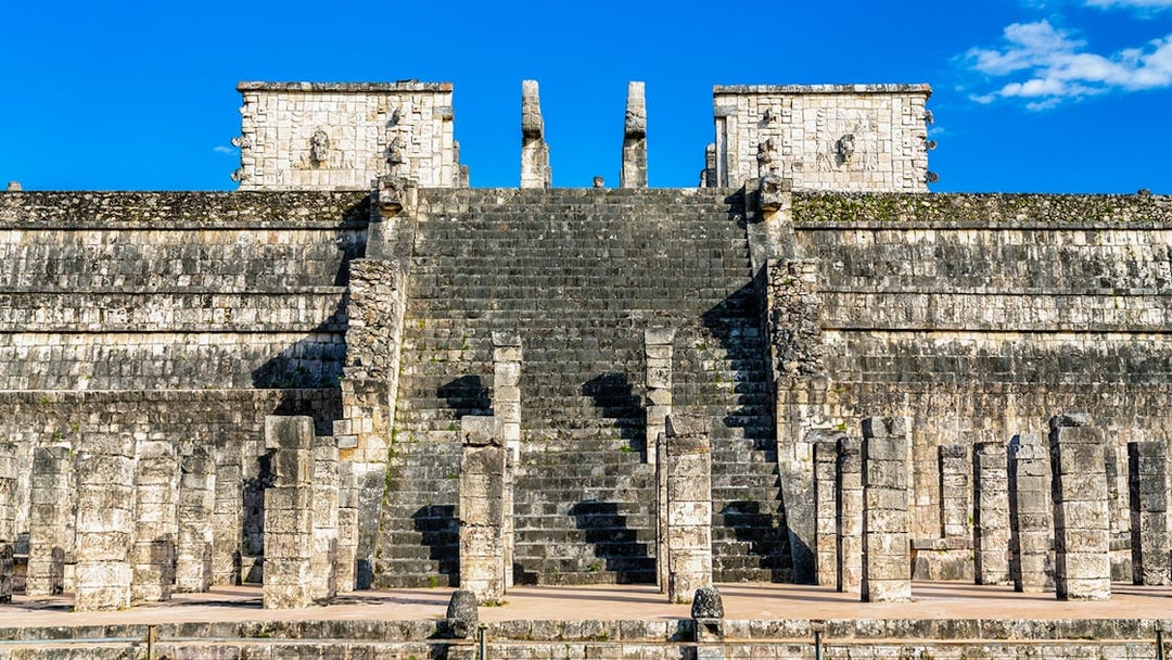 Temple of the Warriors steps and columns at Chichen Itza under a clear blue sky.