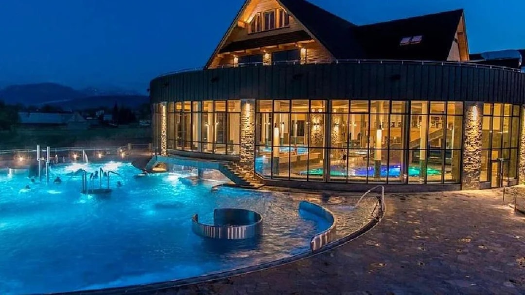 Chocholow Thermal Baths Saunarium illuminated at night with outdoor pools.