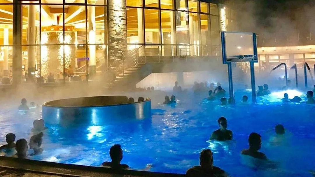 Visitors enjoying the illuminated pools at Chocholow Thermal Baths Saunarium at night.