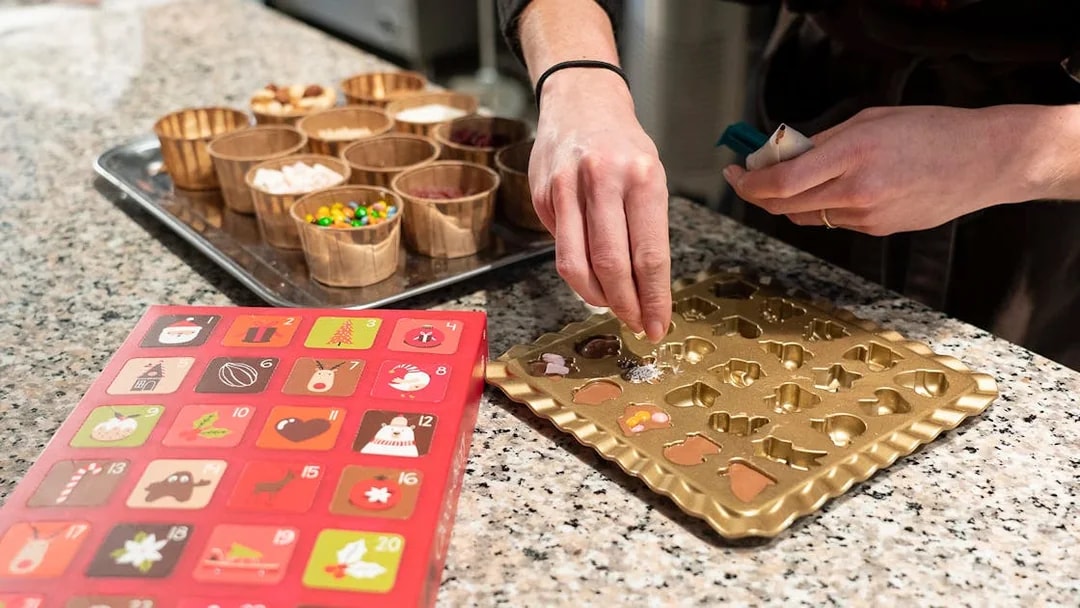 Close up of hands decorating chocolates in a mold at a Chocolate Tablet Workshop.