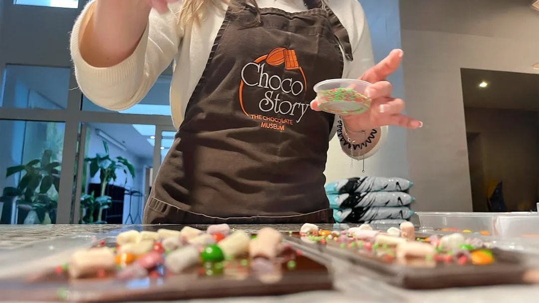 Person decorating chocolate bars at Chocolate Tablet Workshop.