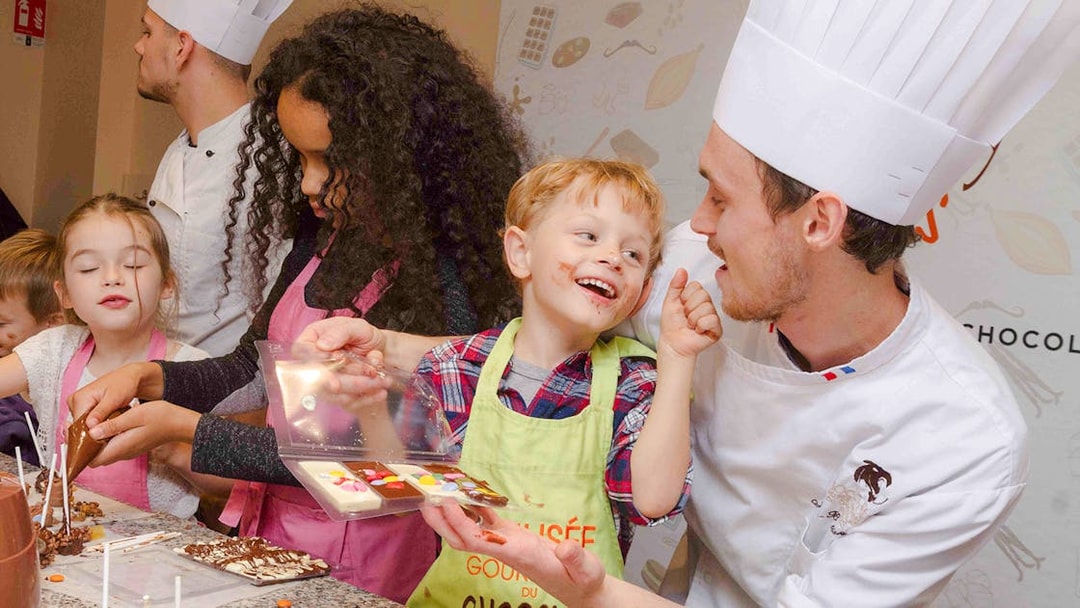 Kids making chocolate with a chef at Choco-Story Paris.