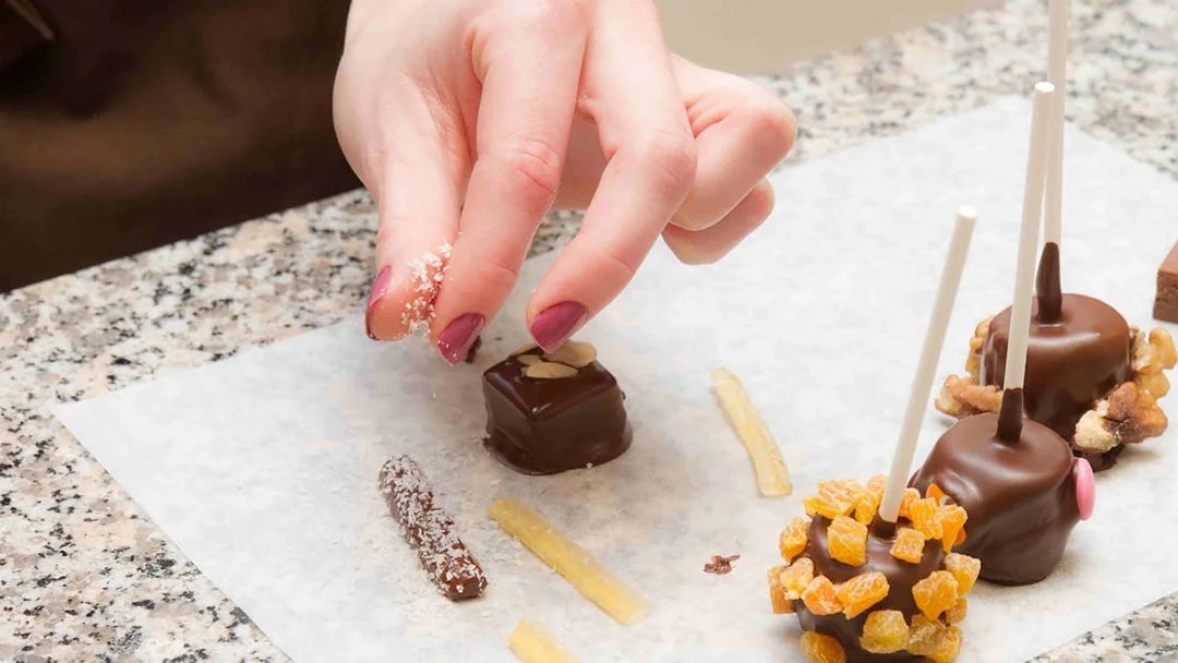 Hand decorating chocolates with toppings at Choco-Story Paris.