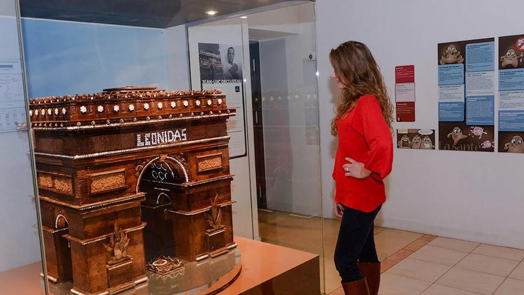 Woman observing chocolate Arc de Triomphe at Choco-Story Paris museum.
