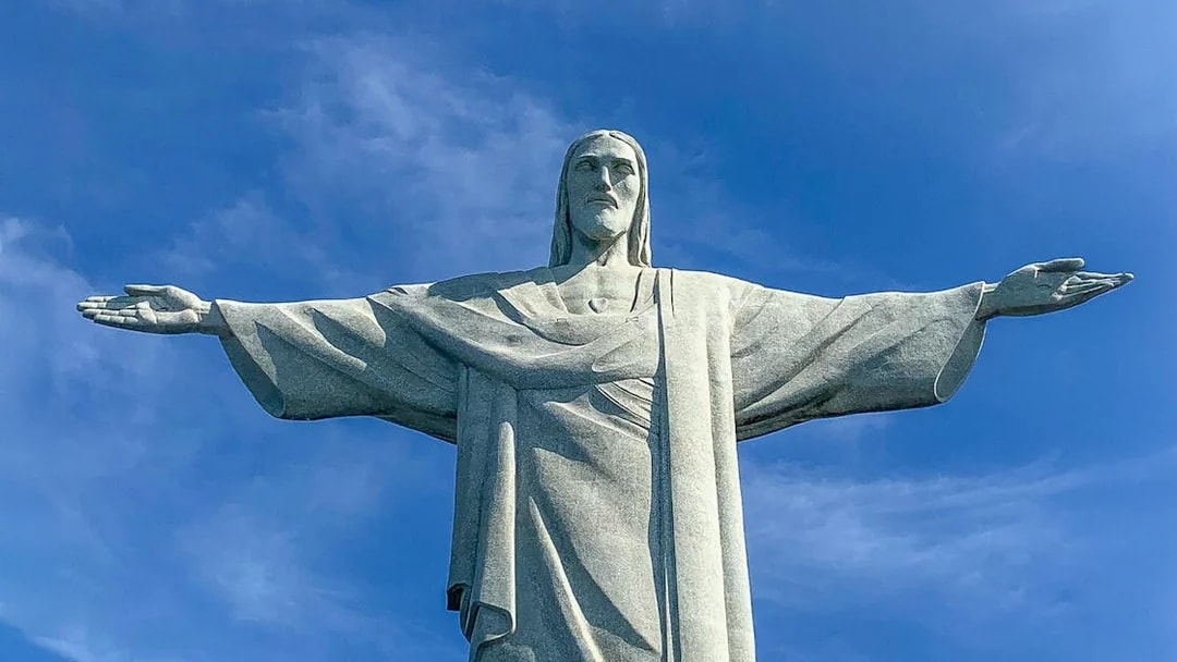 Christ the Redeemer statue with arms outstretched against blue sky, Rio de Janeiro.