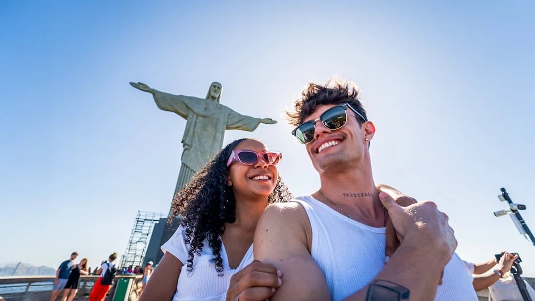 Couple smiling in front of Christ the Redeemer statue, Rio de Janeiro.