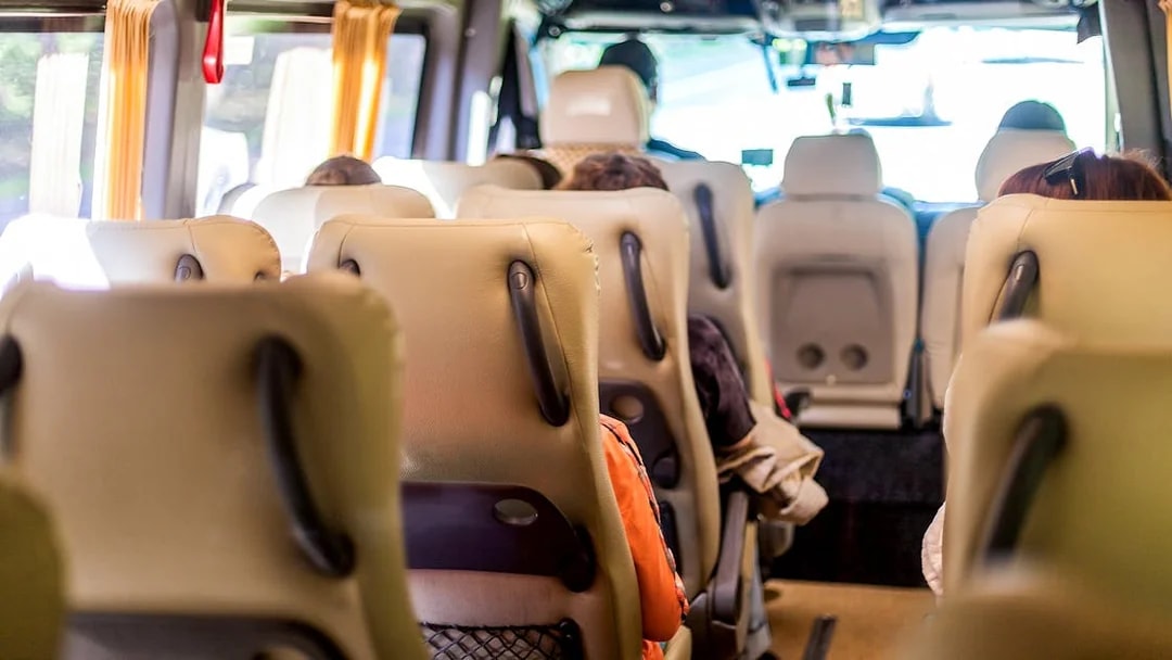Minivan interior with beige seats and passengers seated, view towards the front.