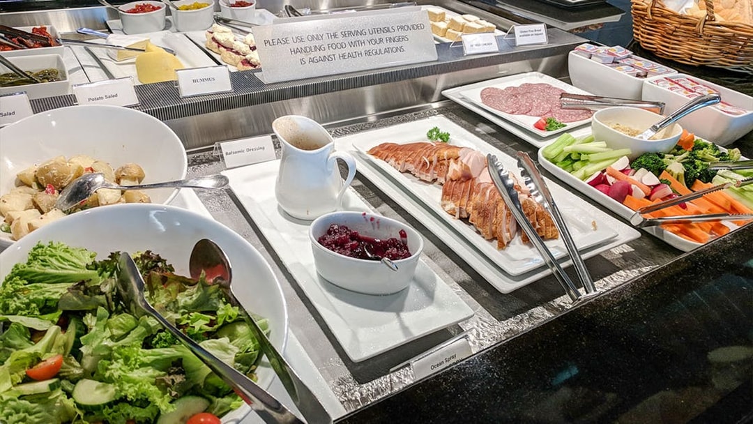 Buffet spread at Plaza Premium Lounge with salads, cold cuts, and condiments.
