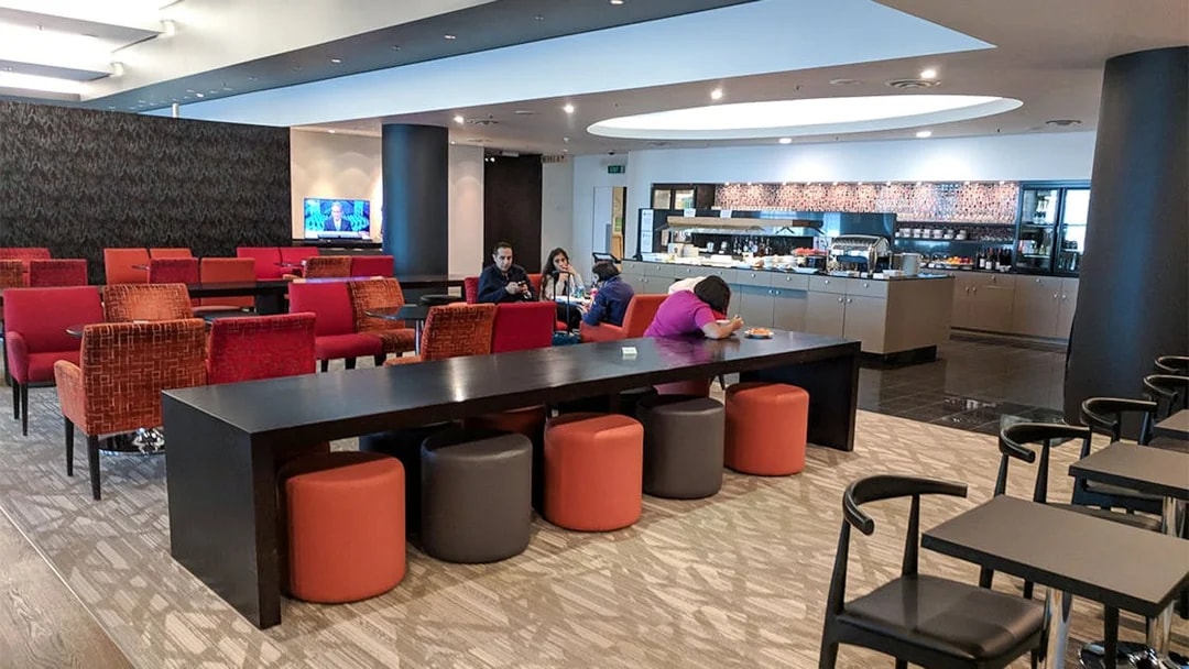 Plaza Premium Lounge seating area with guests and buffet in the background.