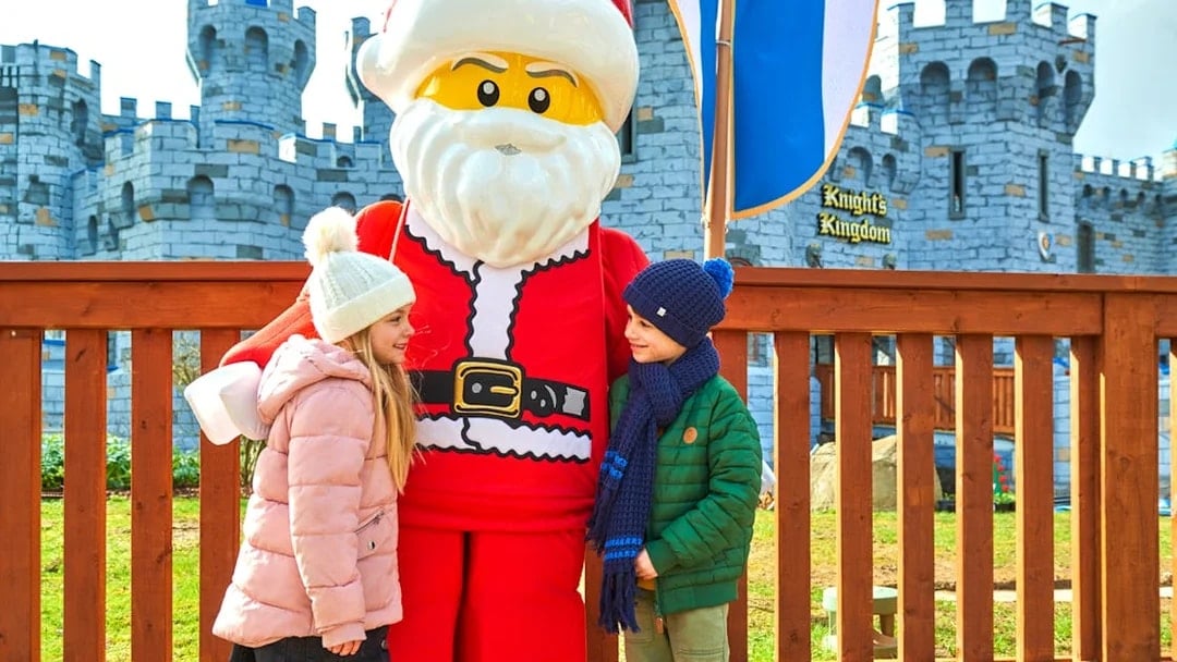 Children meeting Lego Santa at Legoland Christmas, London with castle backdrop.