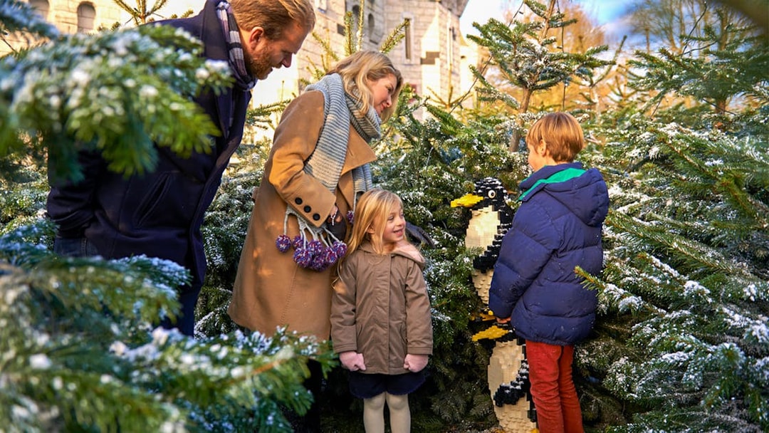Family exploring Lego penguin display at Legoland Christmas, London.