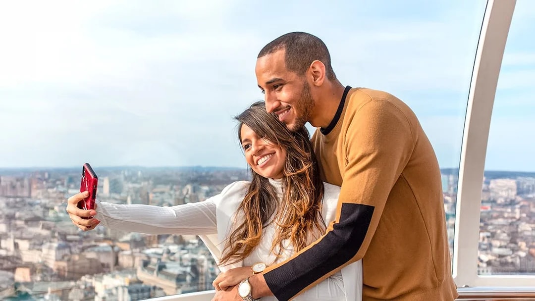Visitors taking a selfie on the London Eye with cityscape views.