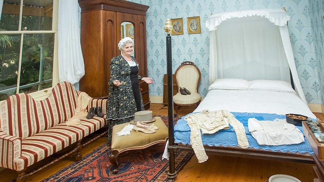 Period-dressed guide in historic bedroom at Churchill Island, Phillip Island Nature Parks.