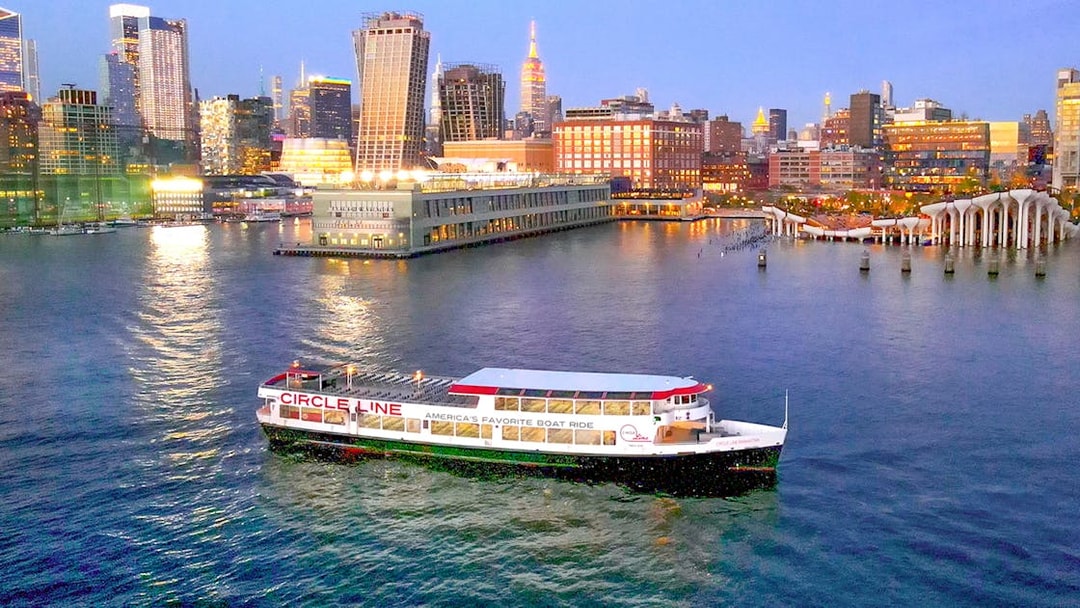 Circle Line cruise boat on Hudson River with New York City skyline at dusk.