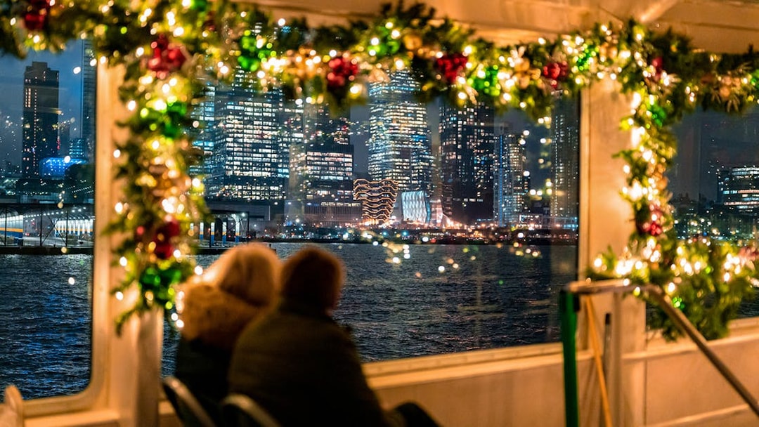Couple enjoying New York City skyline from decorated boat on Circle Line Harbor Lights Cruise.