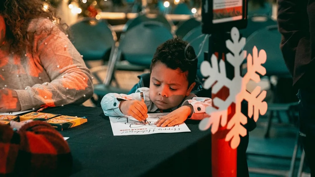 Child coloring at a holiday-themed event during the Circle Line: Harbor Lights Cruise.