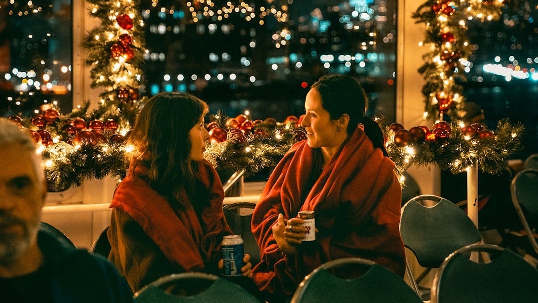 Two people enjoying a festive evening on the Circle Line Harbor Lights Cruise.