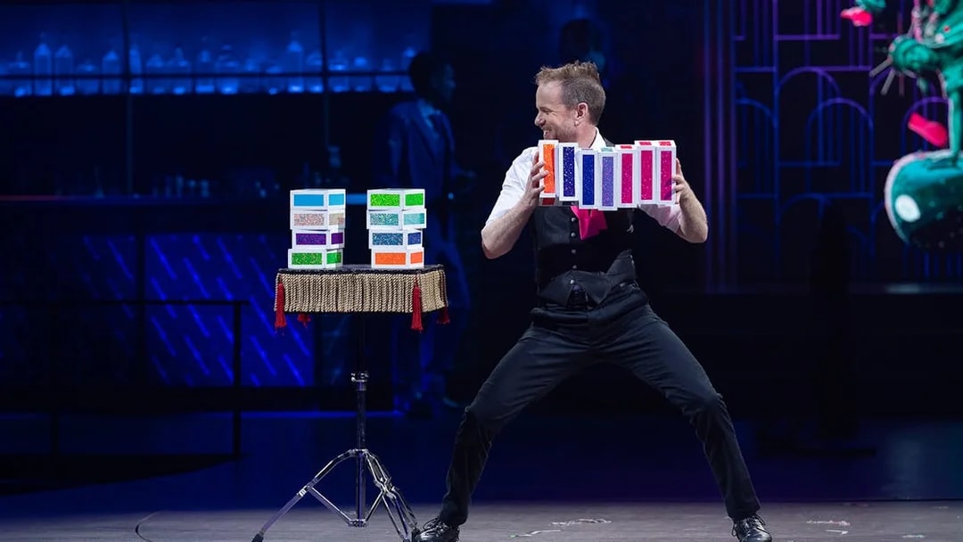 Performer showcasing a colorful card trick at Mad Apple show.