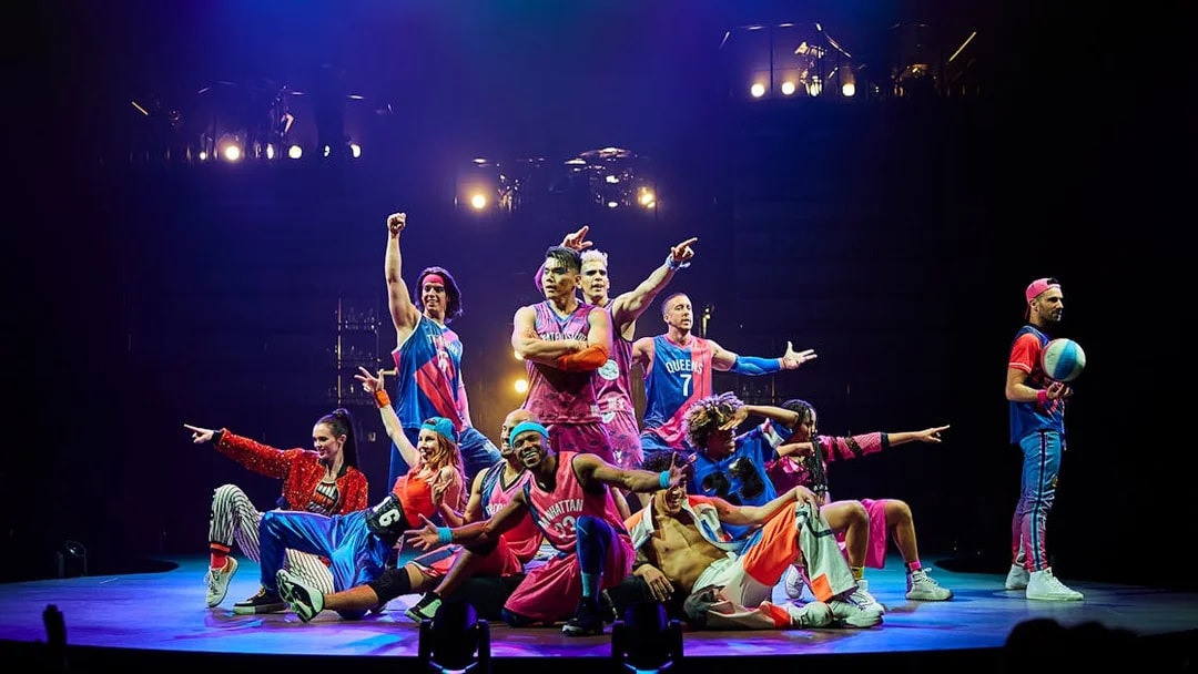Performers in colorful costumes on stage during Mad Apple show.