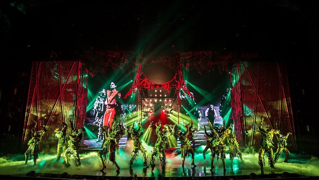 Performers on stage at Michael Jackson ONE show with vibrant lights and costumes.