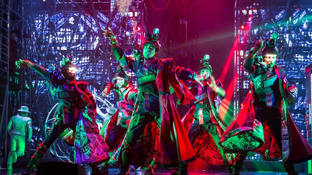 Performers in vibrant costumes dance energetically on stage at Michael Jackson ONE show.