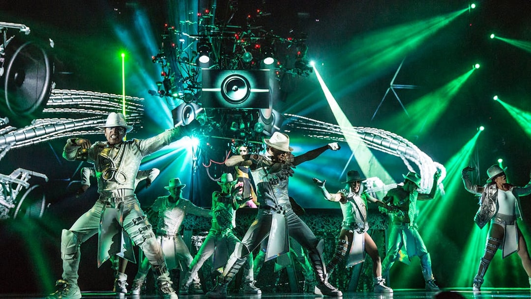 Performers dancing in Michael Jackson ONE show with vibrant green lights.