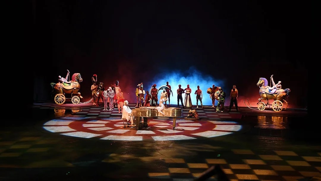 Performers on stage with colorful costumes and props in a theatrical show.