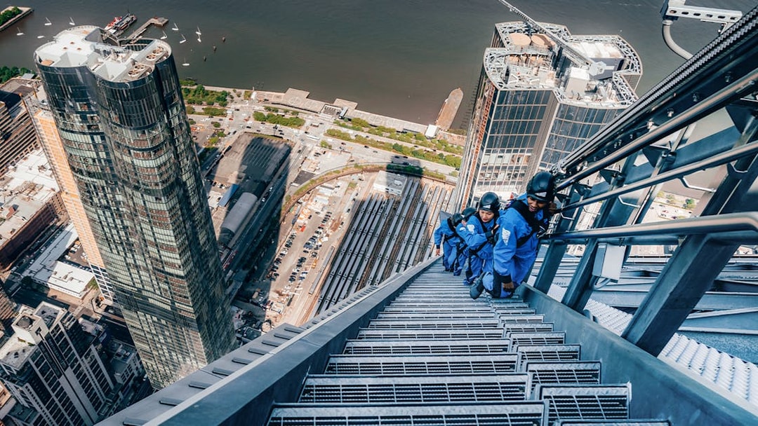 Climbers ascending a skyscraper in Sydney with cityscape and harbor views.