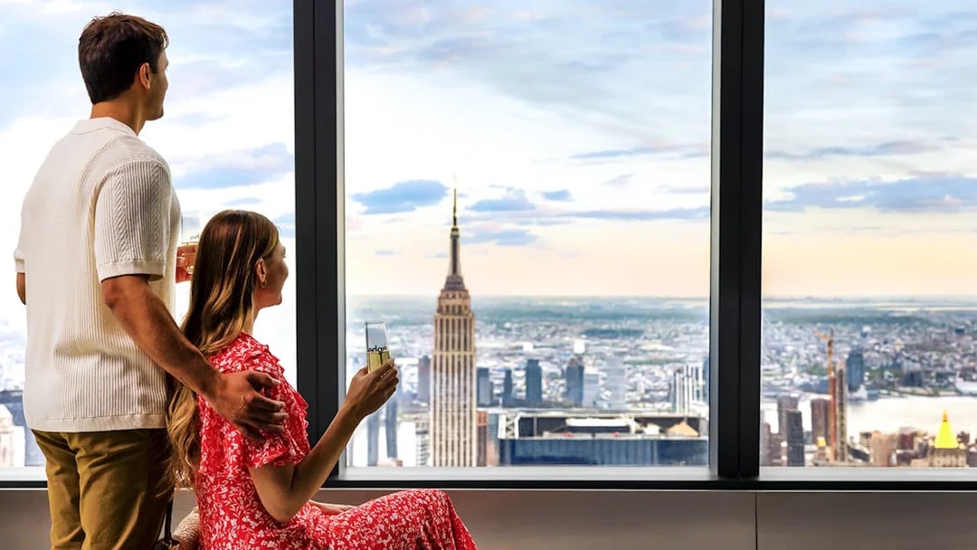 Tourists at Edge Observation Deck enjoying city view with Empire State Building.