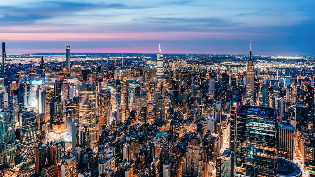 Aerial view of New York City skyline at dusk, highlighting skyscrapers and city lights.