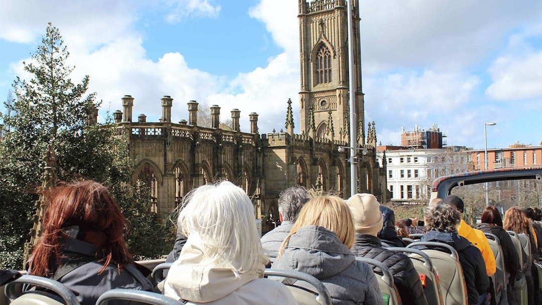 Passengers on open-top bus tour passing St. Luke's Church, Liverpool.