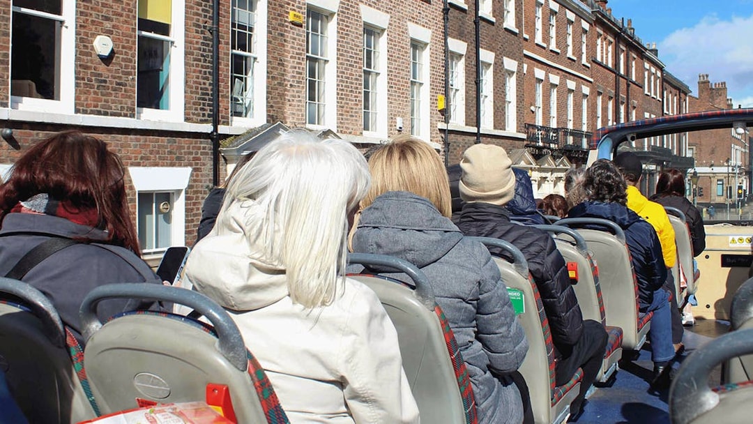 Passengers on open-top bus tour in Liverpool city.
