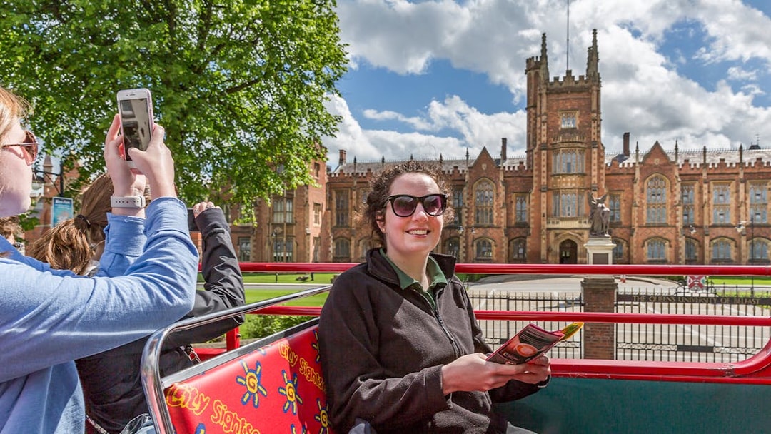 HOHO tour bus at Queen's University, Belfast with passengers enjoying the view.