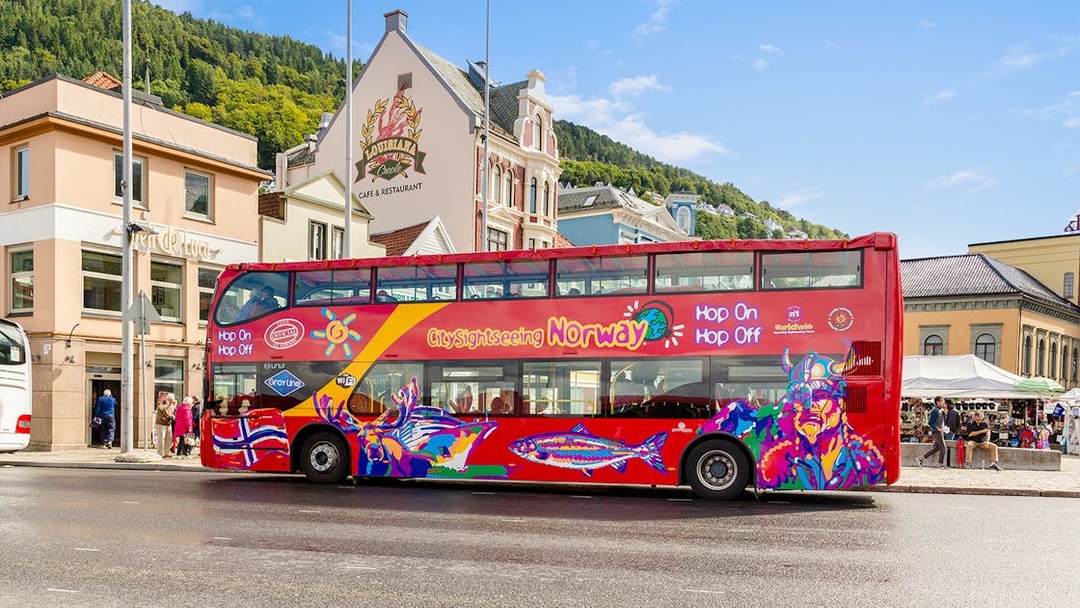 Bergen city sightseeing bus with colorful design parked near historic buildings.