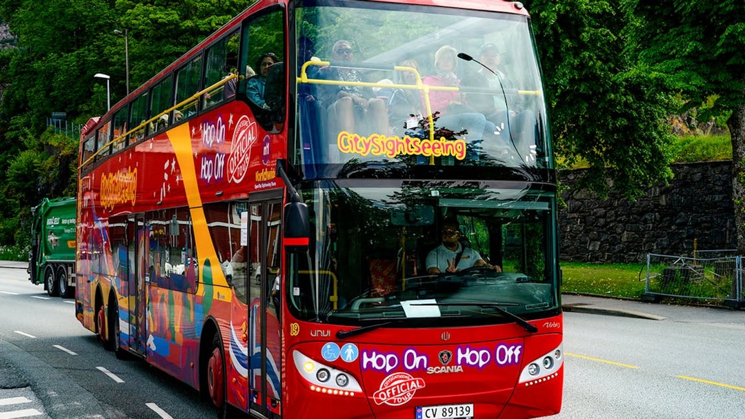 Bergen city sightseeing double-decker bus on a tree-lined street.