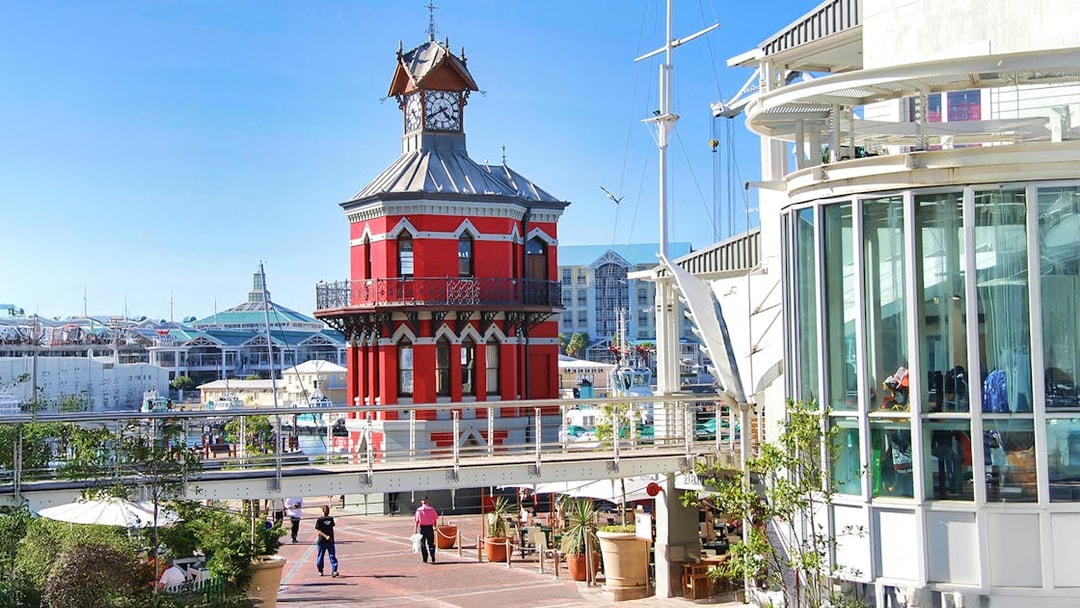 Clock tower at V&A Waterfront, Cape Town, with HopOn HopOff bus tour route nearby.