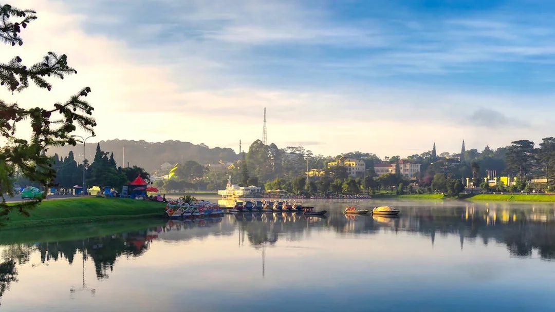 Xuan Huong Lake in the morning with boats and distant buildings in Da Lat, Vietnam.