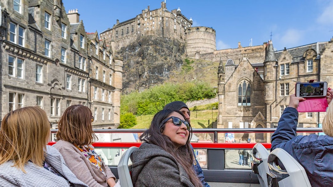 Edinburgh Castle viewed from a hop-on hop-off tour bus with tourists.