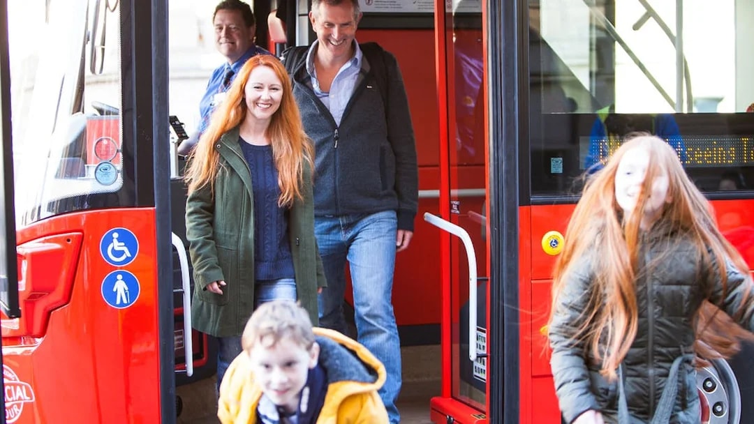 Passengers exiting a red bus during Edinburgh Hop-On Hop-Off Tour.