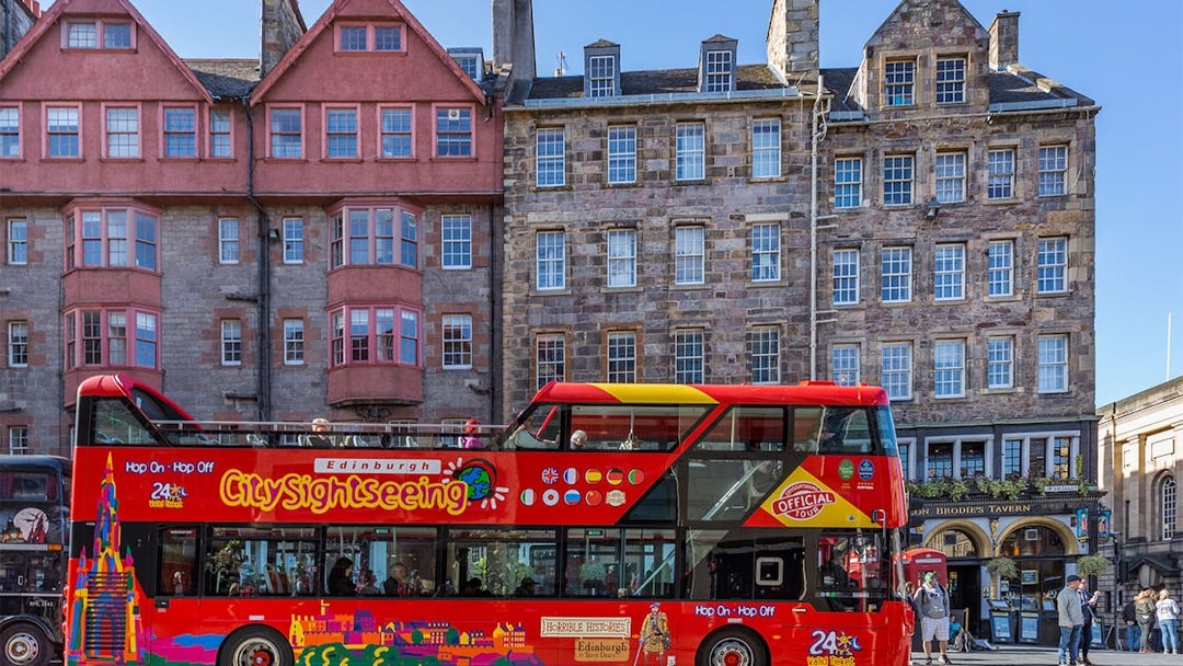 Edinburgh hop-on hop-off tour bus in front of historic buildings.