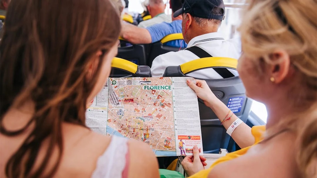 Tourists on Florence sightseeing bus holding city map.