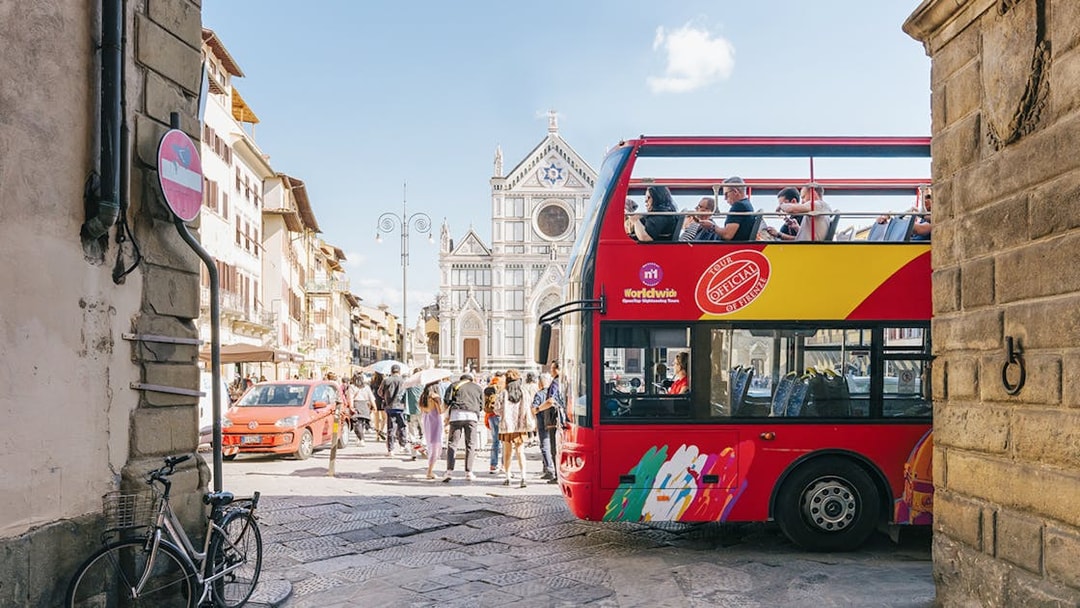 Open-top tour bus near Basilica di Santa Croce in Florence alley.