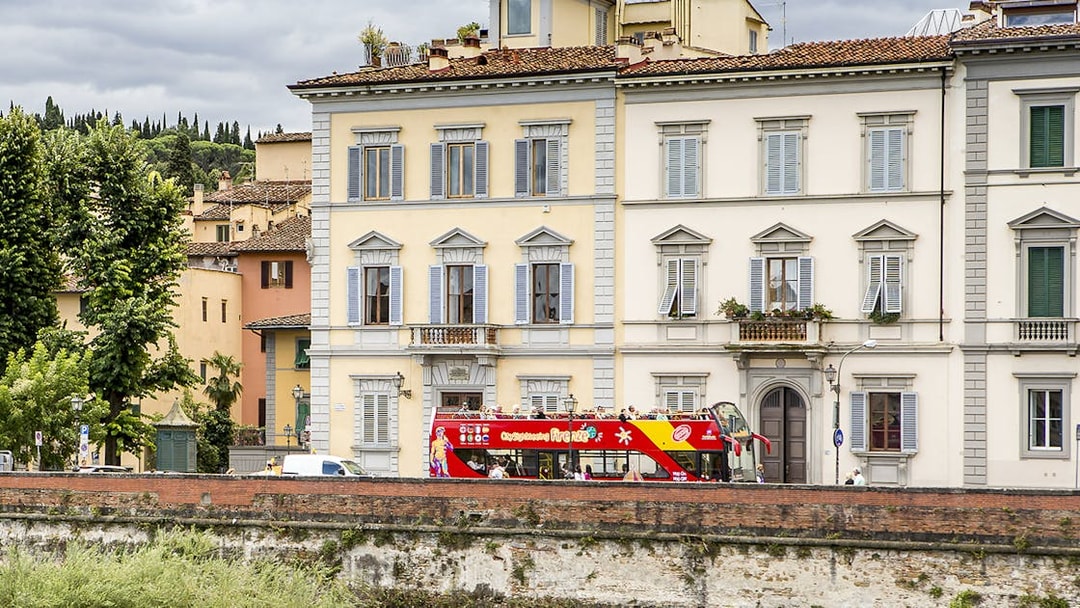 HOHO tour bus passing by historic buildings near Hotel Embassy, Florence.