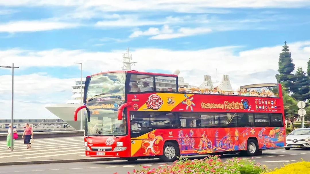 Hop-on hop-off bus tour in Funchal, Madeira, with cruise ship in background.