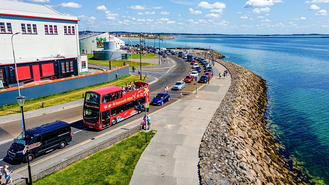 Double-decker bus on Galway Hop-On-Hop-Off Tour passing by the beach.