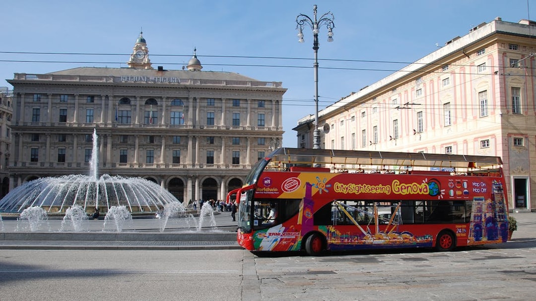 Hop-on-hop-off bus in front of Piazza De Ferrari fountain, Genoa.