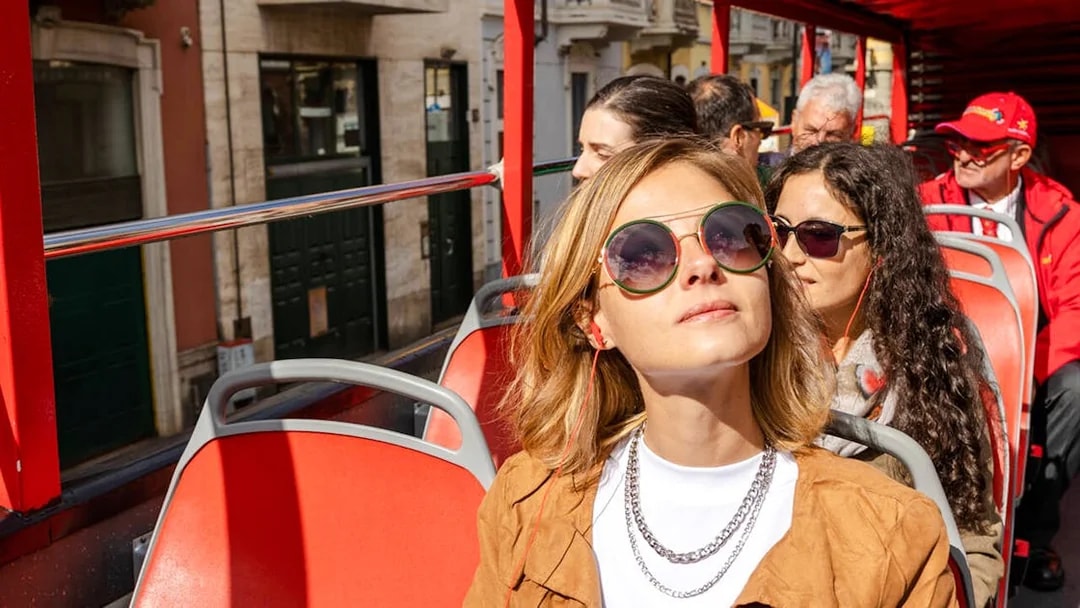 Sightseeing tourists on an open-top bus in Italy enjoying the city views.